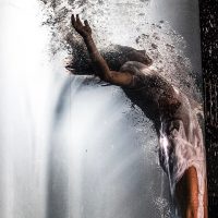 Eine Frau in einem gefüllten Wasserbecken, während sie langsam mit vielen Luftblasen nach unten sinkt.